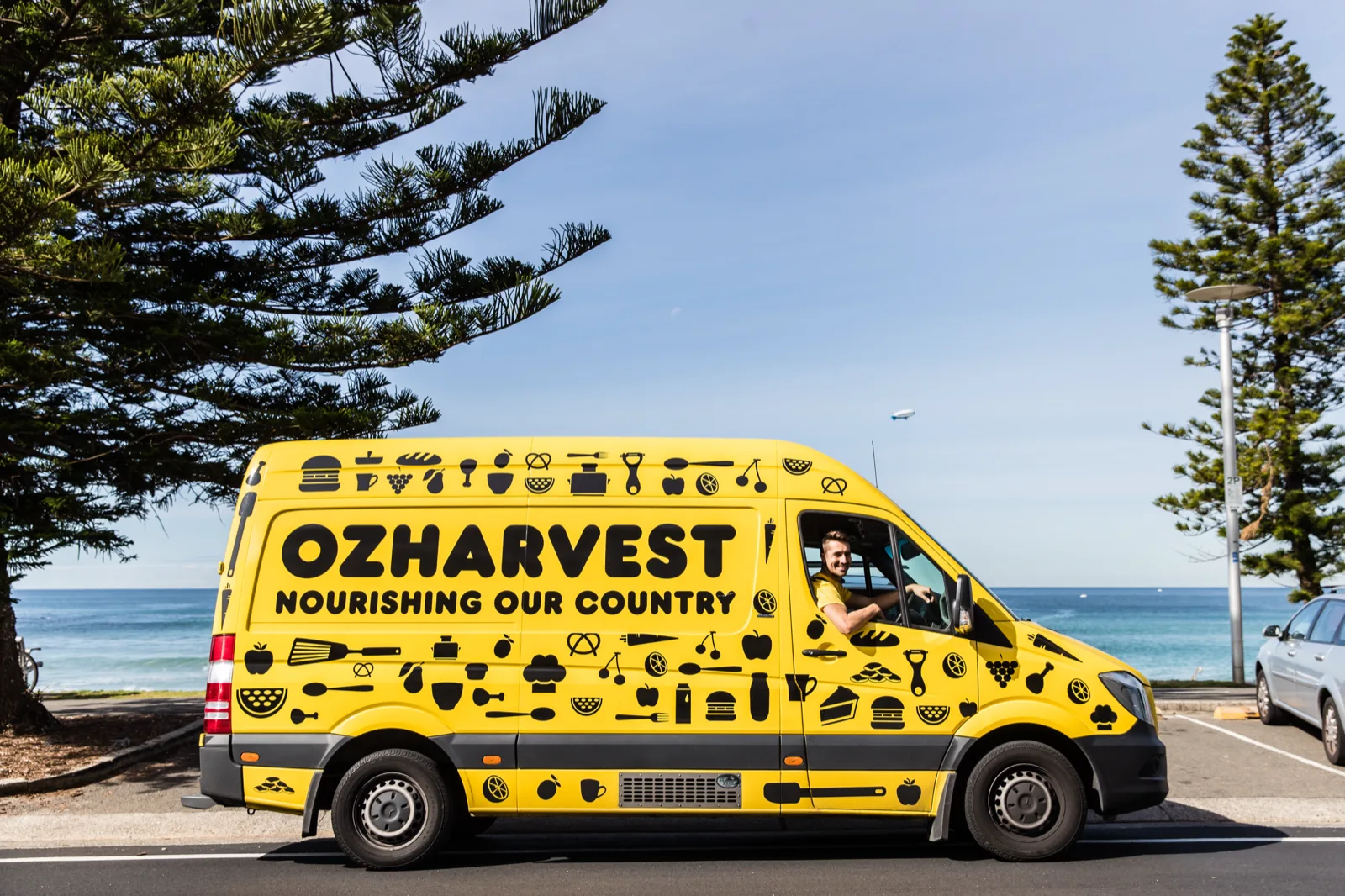 An OzHarvest food rescue van parked beside the beach in Sydney.
